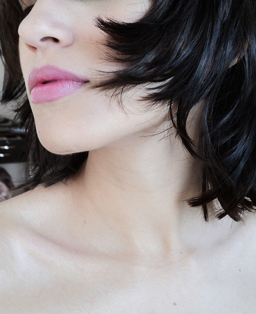 A partial side portrait of a woman with short black hair.
