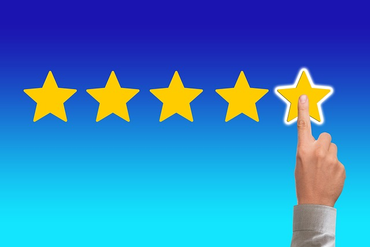 a finger pressing five stars rating on a screen.