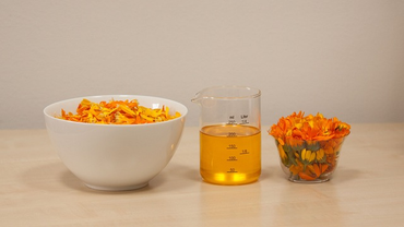 body massage oil with petals in a bowl on left and flower in a glass on right.