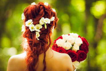 a woman with long red hair holding a bouquet of flowers.