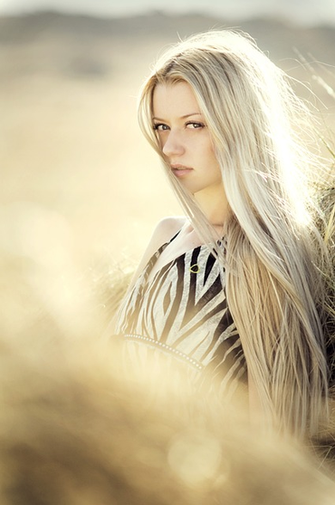 A blond woman with long hair standing outdoors.