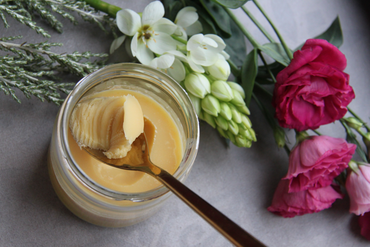 ghee in a glass bottle surrounded by flowers.