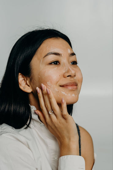 Naturally beautiful woman applying ayurvedic skincare products on her face.
